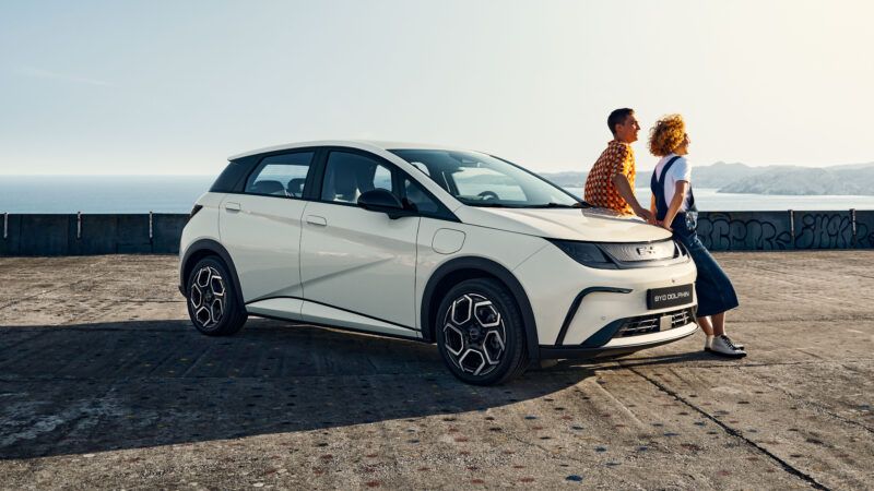 BYD karbantartás: fehér BYD Dolphin parkol a tengerparti betonplaccon, mellette egy pár